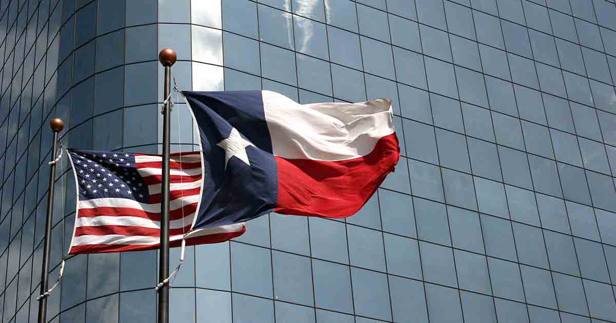 Texas and American flag outside of large building. 