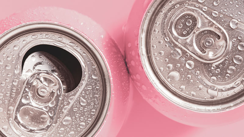 Pink soda cans on a pink background.