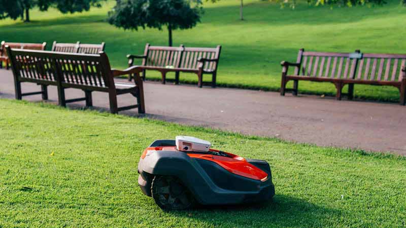 A robot lawn mower in a park.