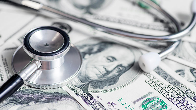 A stethoscope sitting on a pile of money.
