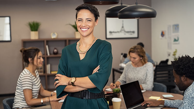Smiling businesswoman with coworkers in the background.