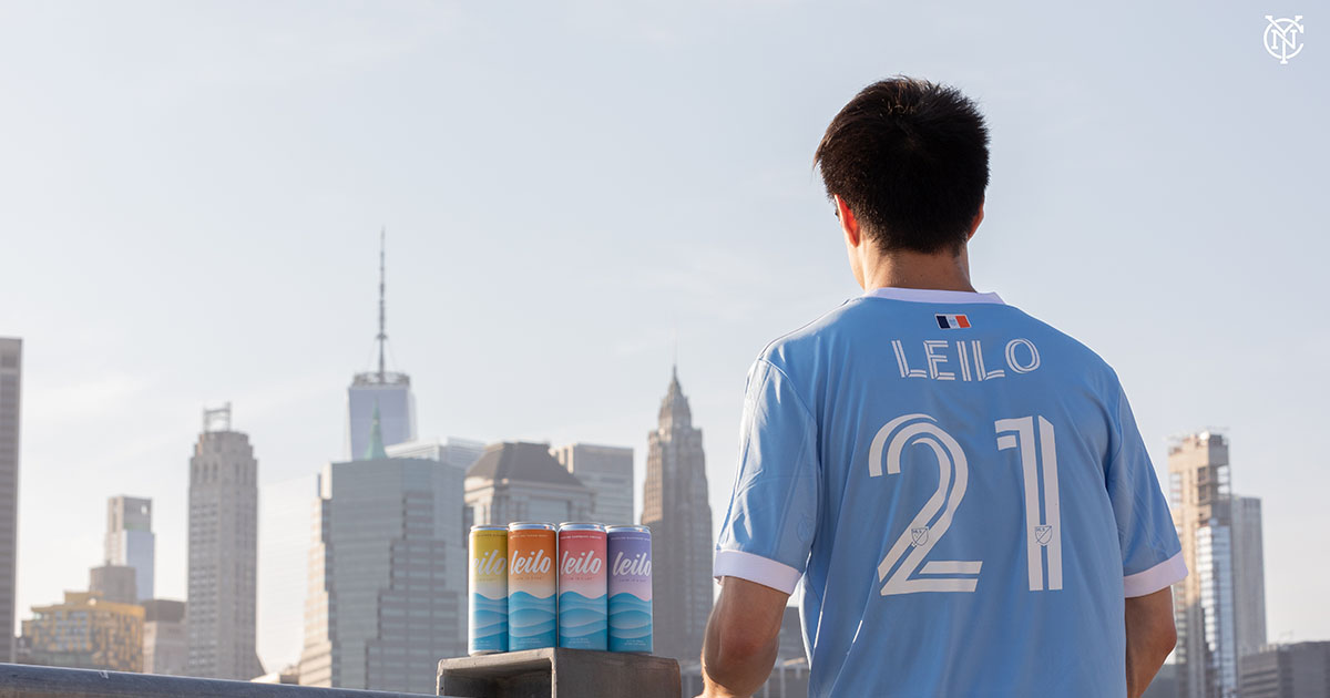 Man wearing Leilo shirt standing next to Leilo cans.