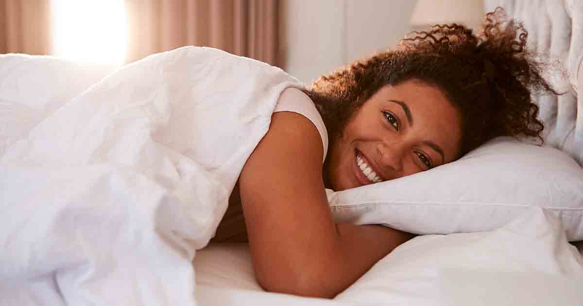 Smiling woman waking up in bed.