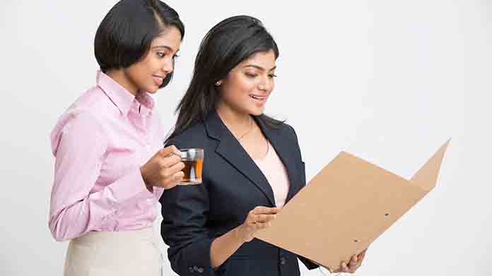 Businesswomen looking at documents in a folder.