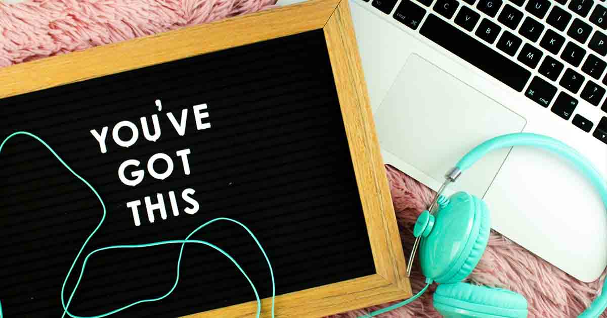 Letter board with text saying, "You've Got This" next to turquoise headphones and laptop.